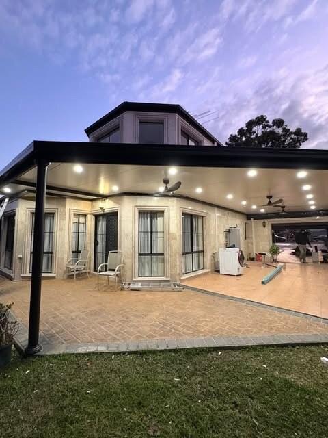 Outdoor patio with recessed lighting and ceiling fans at dusk